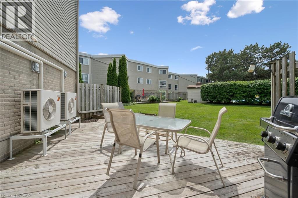 Wood-finish deck with a stone exterior wall and a manicured lawn - 60 Elmsdale Drive Unit# 25, Kitchener, ON - Outdoor With Deck Patio Veranda With Exterior