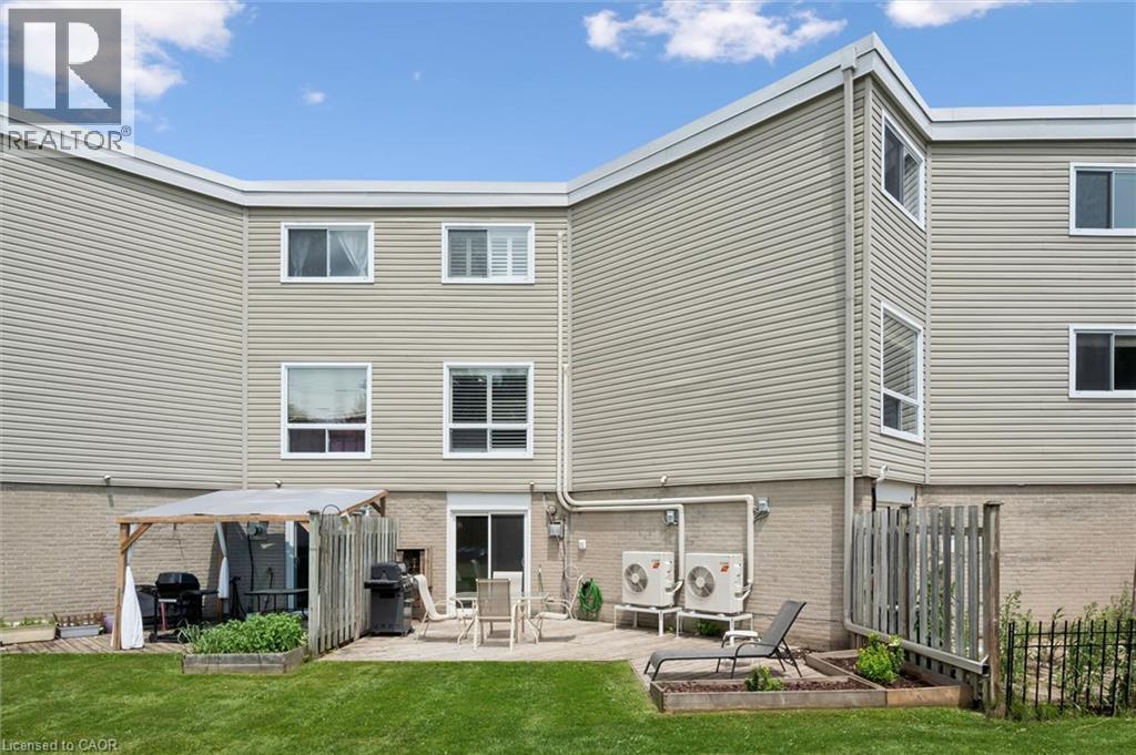 Expansive grassy yard with a paver patio and raised garden beds - 60 Elmsdale Drive Unit# 25, Kitchener, ON - Outdoor With Deck Patio Veranda