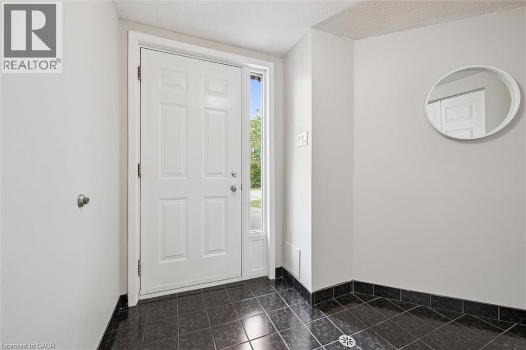 Panel door with a sidelight, dark tile flooring, and light-toned walls - 60 Elmsdale Drive Unit# 25, Kitchener, ON - Indoor Photo Showing Other Room