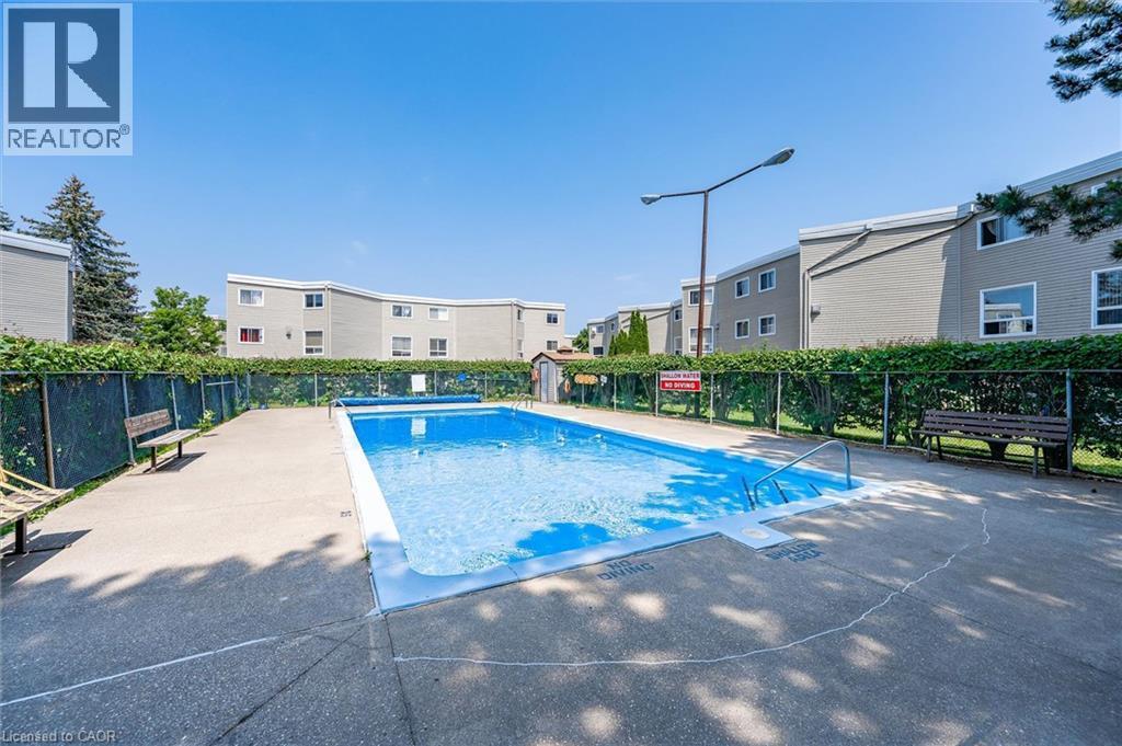 Outdoor swimming pool with concrete surround - 60 Elmsdale Drive Unit# 25, Kitchener, ON - Outdoor With In Ground Pool With Backyard