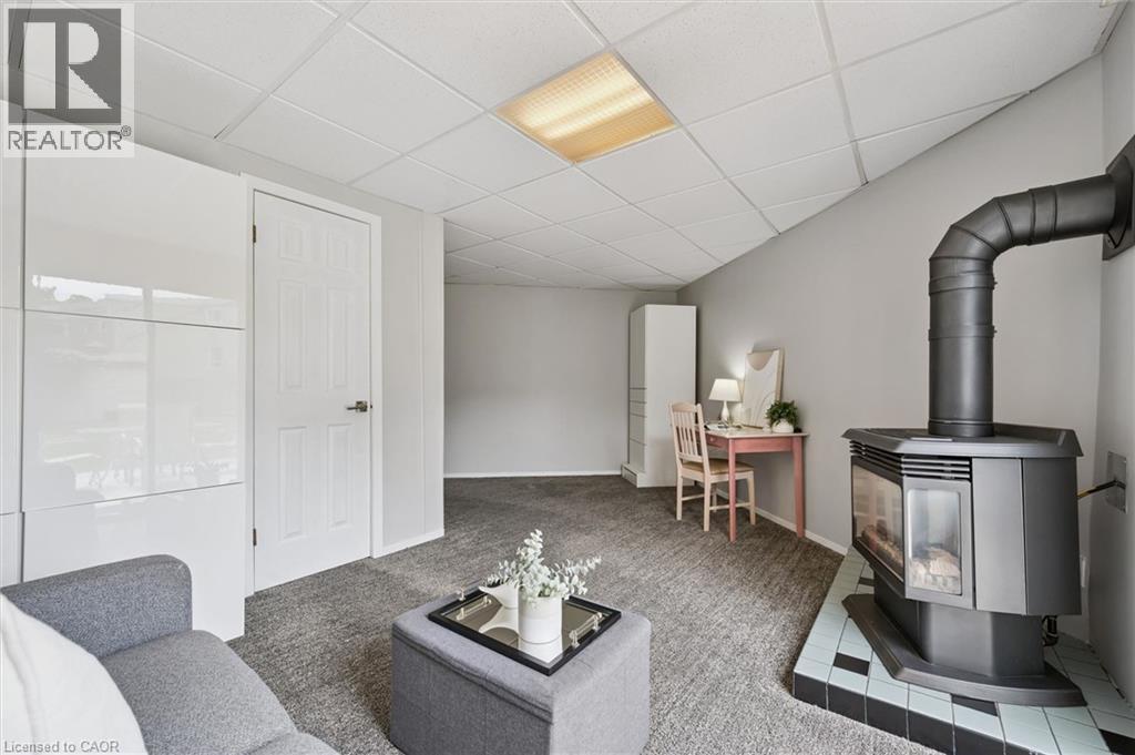 Compact room featuring a built-in fireplace, drop ceiling, light gray walls, and carpet flooring - 60 Elmsdale Drive Unit# 25, Kitchener, ON - Indoor