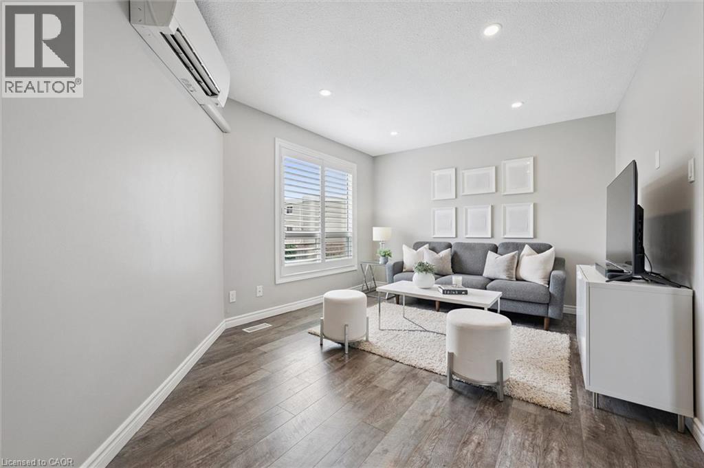 Spacious interior featuring wood-finish flooring, recessed lighting, and a window with plantation shutters - 60 Elmsdale Drive Unit# 25, Kitchener, ON - Indoor Photo Showing Living Room