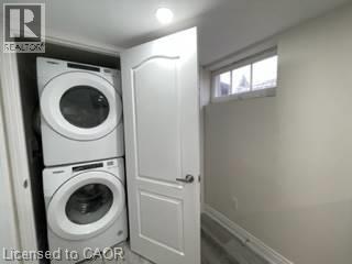 Stacked washer and dryer units, overhead recessed lighting, and a white interior door with dark hardware - 15 Pinecrest Drive Unit# Lower, Kitchener, ON - Indoor Photo Showing Laundry Room