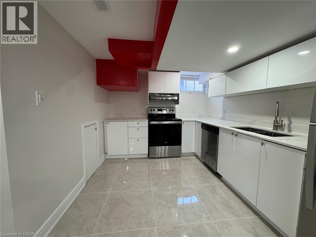 Recessed lighting illuminates the kitchen featuring a stainless steel appliance suite, white cabinetry, integrated sink, and light-toned tile flooring - 15 Pinecrest Drive Unit# Lower, Kitchener, ON - Indoor Photo Showing Kitchen With Double Sink