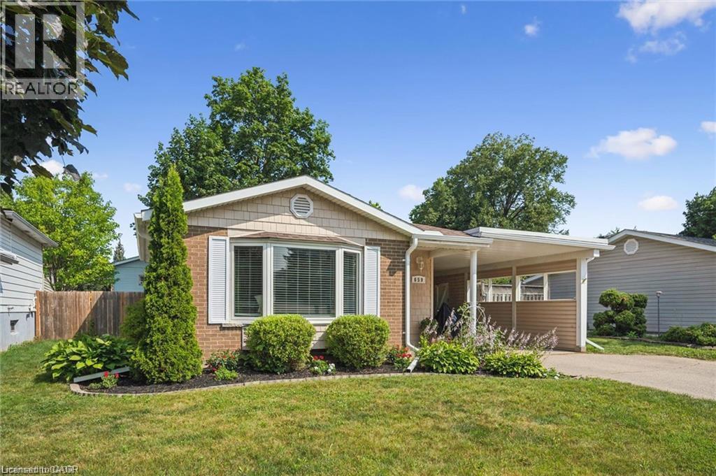 Charming brick ranch home featuring a covered front porch, expansive picture windows with contemporary framing, manicured landscaping with mature trees and established plantings, a wide driveway, and - 659 Glen Forrest Boulevard, Waterloo, ON - Outdoor