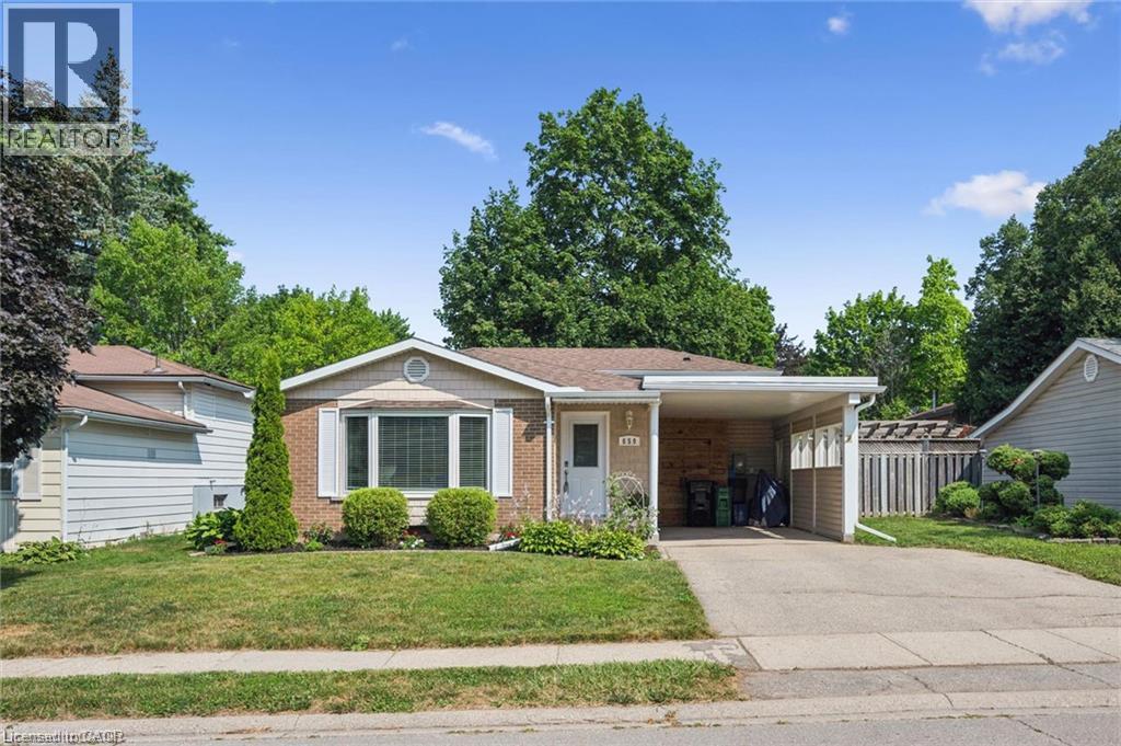 Charming brick ranch home featuring a welcoming front facade with covered entry portico, two-car attached garage, and mature landscaping throughout the grounds - 659 Glen Forrest Boulevard, Waterloo, ON - Outdoor With Facade