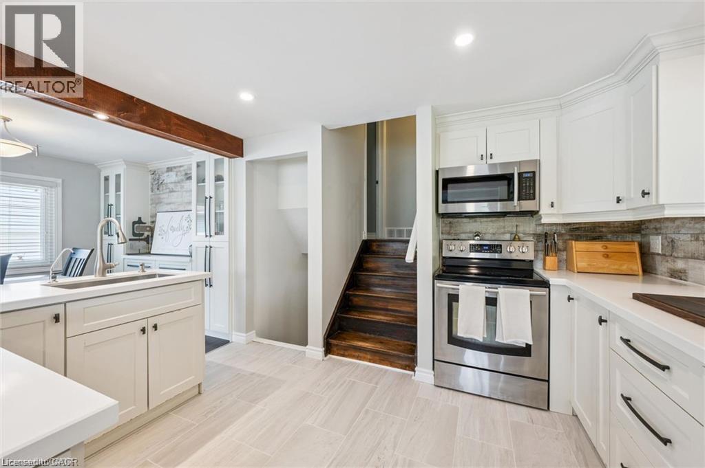 Renovated kitchen featuring white cabinetry, stainless steel appliances, wood-finish countertops, subway tile backsplash, and light wood-finish flooring - 659 Glen Forrest Boulevard, Waterloo, ON - Indoor Photo Showing Kitchen
