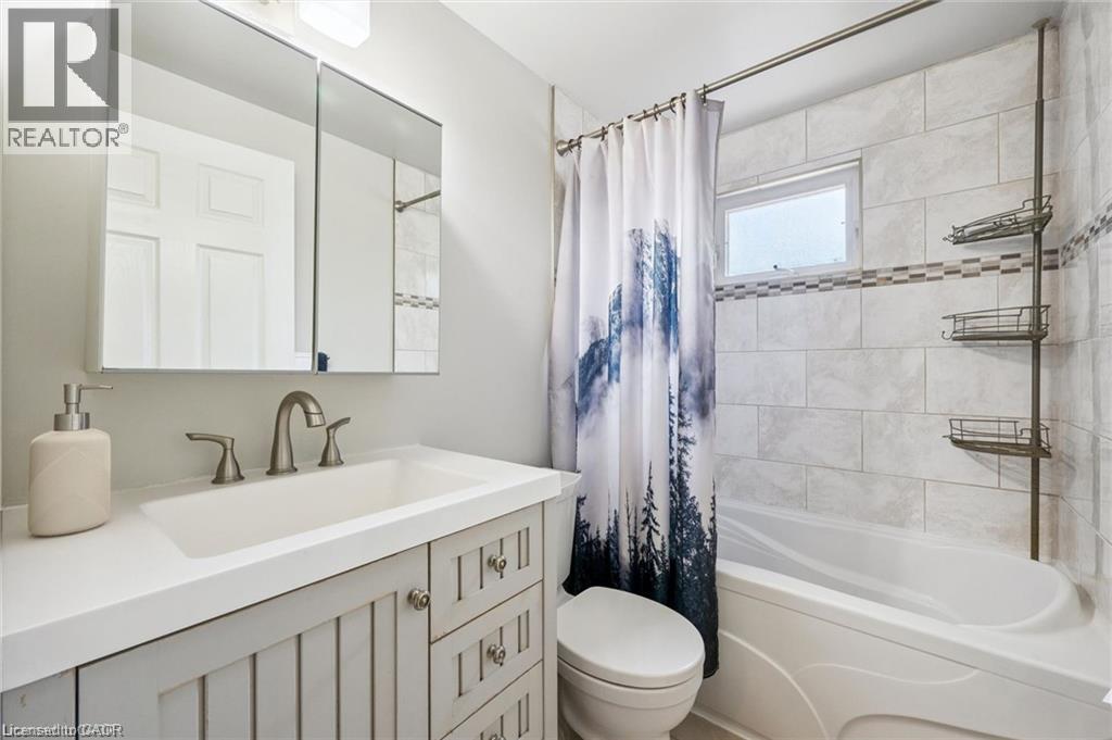 Spa-inspired bathroom featuring a vanity with multiple drawers and brushed nickel hardware, white subway tile surround, polished countertop, and dual wall-mounted shelving - 659 Glen Forrest Boulevard, Waterloo, ON - Indoor Photo Showing Bathroom