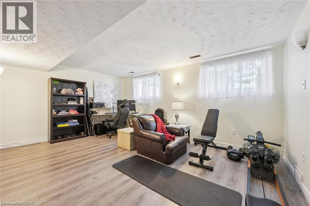 Finished basement recreation space featuring engineered wood-finish flooring, recessed ceiling lighting, and large windows with sheer treatments - 659 Glen Forrest Boulevard, Waterloo, ON - Indoor