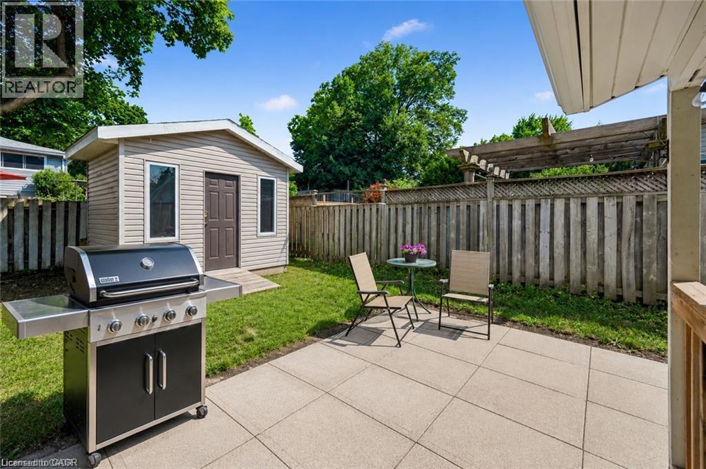 Expansive backyard oasis featuring a concrete patio, built-in gas grill with stainless steel accents, mature landscaping with lush lawn, wooden privacy fencing, and a detached garden shed with functio - 659 Glen Forrest Boulevard, Waterloo, ON - Outdoor With Deck Patio Veranda With Exterior