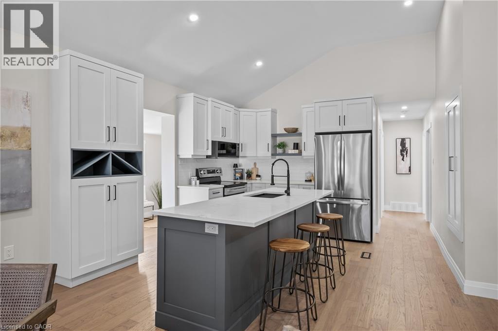 Kitchen featuring a center island, stainless steel appliances, white cabinetry, and wood-finish flooring - 1041 Shepherd'S Drive, Burlington, ON - Indoor Photo Showing Kitchen With Upgraded Kitchen