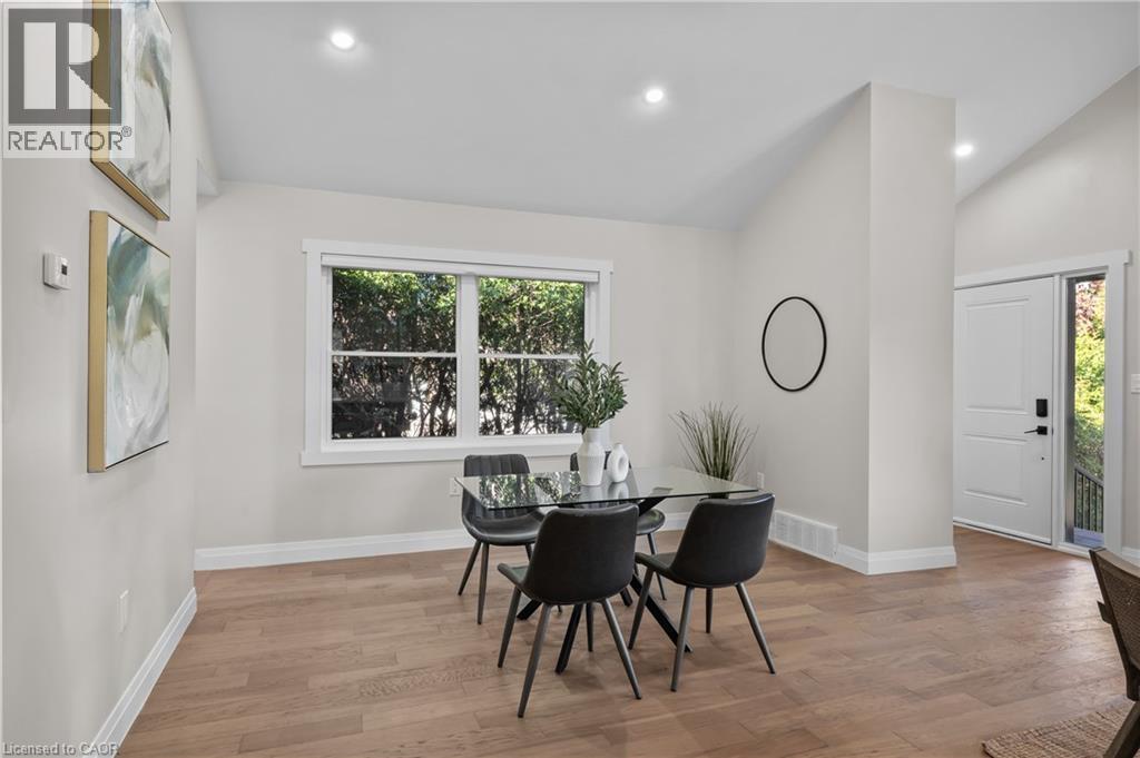 Bright, open dining area showcasing wood-finish flooring, large multi-pane windows with natural light, recessed ceiling lighting, and clean white walls with crisp architectural detailing - 1041 Shepherd'S Drive, Burlington, ON - Indoor