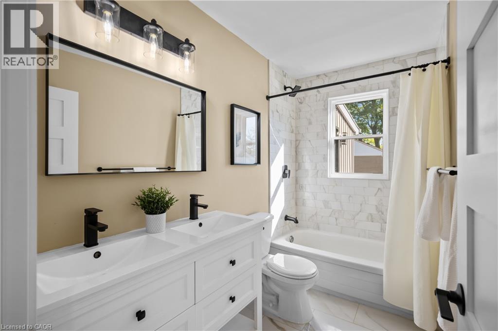 Dual vanity with matte black faucets, framed mirror, and three-light fixture - 1041 Shepherd'S Drive, Burlington, ON - Indoor Photo Showing Bathroom