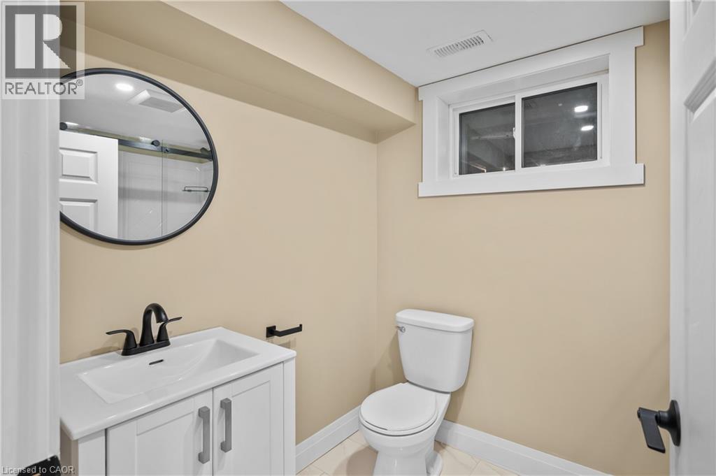 Bathroom featuring a white vanity with integrated sink, matte black faucet, and a round black-framed mirror - 1041 Shepherd'S Drive, Burlington, ON - Indoor Photo Showing Bathroom