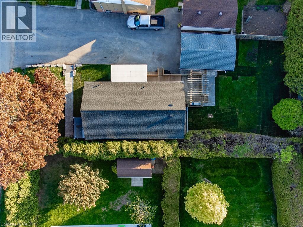 Expansive property featuring a paved driveway, a shingled roof, a wooden deck, a pergola, and mature trees - 1041 Shepherd'S Drive, Burlington, ON - Outdoor