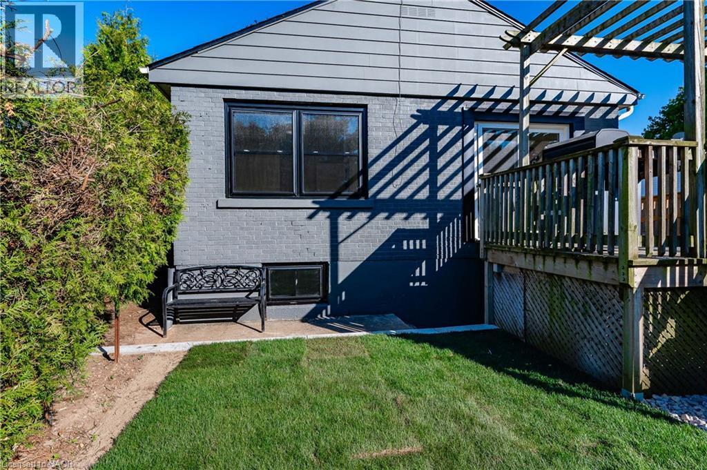 Sophisticated outdoor living space featuring a manicured lawn, mature landscaping with evergreen hedging, a multi-level composite deck with built-in railings, pergola structure providing shade, and di - 1041 Shepherd'S Drive, Burlington, ON - Outdoor