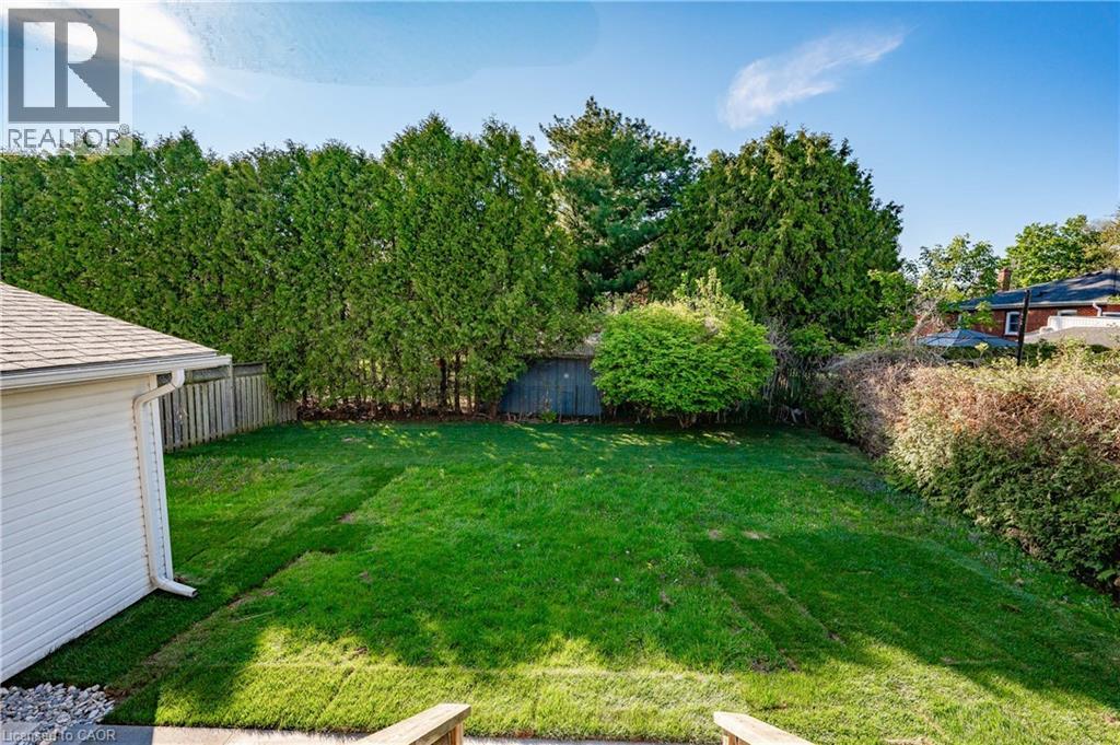 Expansive backyard featuring a manicured lawn, mature privacy trees lining the perimeter, and a detached garage - 1041 Shepherd'S Drive, Burlington, ON - Outdoor