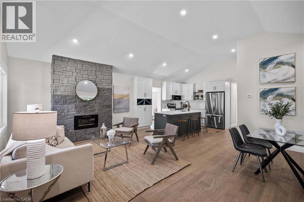 Open-concept living area featuring wood-finish flooring throughout, recessed ceiling lighting, and a stone fireplace accent wall with integrated fireplace - 1041 Shepherd'S Drive, Burlington, ON - Indoor Photo Showing Living Room With Fireplace