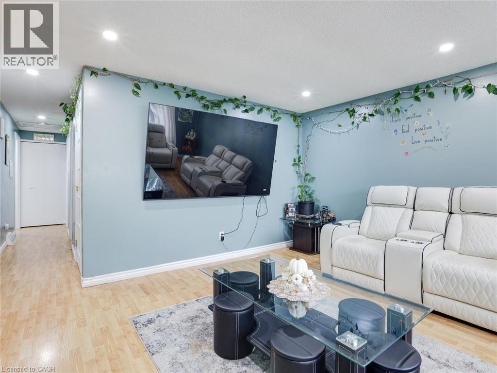 Modern recreation room featuring recessed ceiling lighting, light wood-finish flooring, and a wall-mounted flat-screen display - 128 Macatee Place, Cambridge, ON - Indoor Photo Showing Living Room