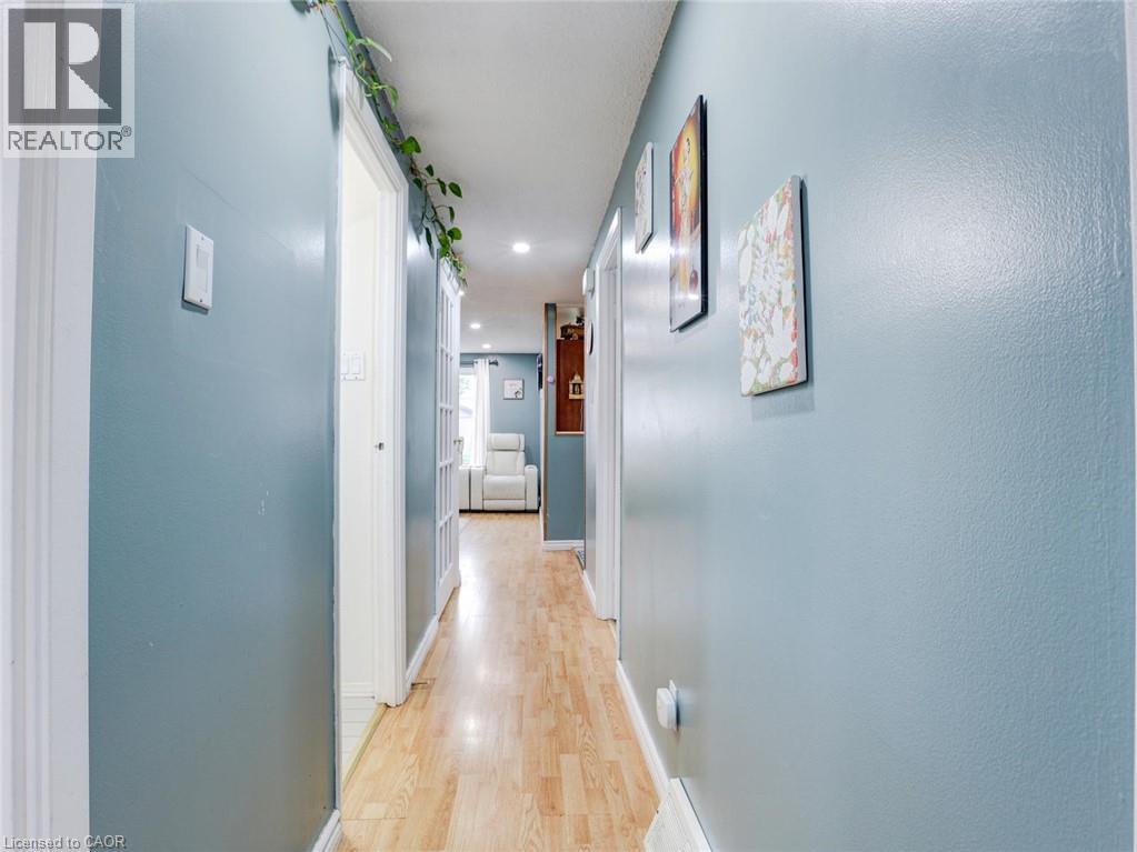 Modern hallway featuring soft blue-painted walls, wood-finish flooring, recessed ceiling lighting, and white trim throughout - 128 Macatee Place, Cambridge, ON - Indoor Photo Showing Other Room