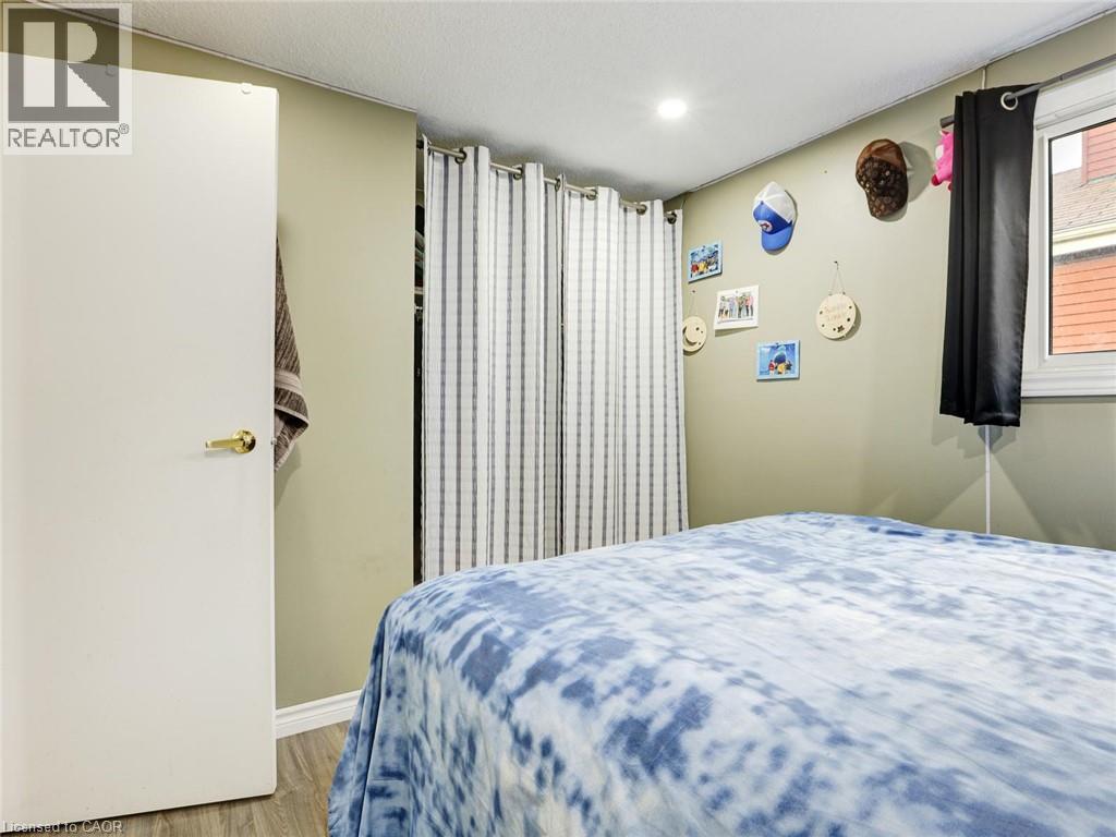 Comfortable bedroom featuring soft blue patterned bedding, wood-finish flooring, and neutral walls - 128 Macatee Place, Cambridge, ON - Indoor Photo Showing Bedroom
