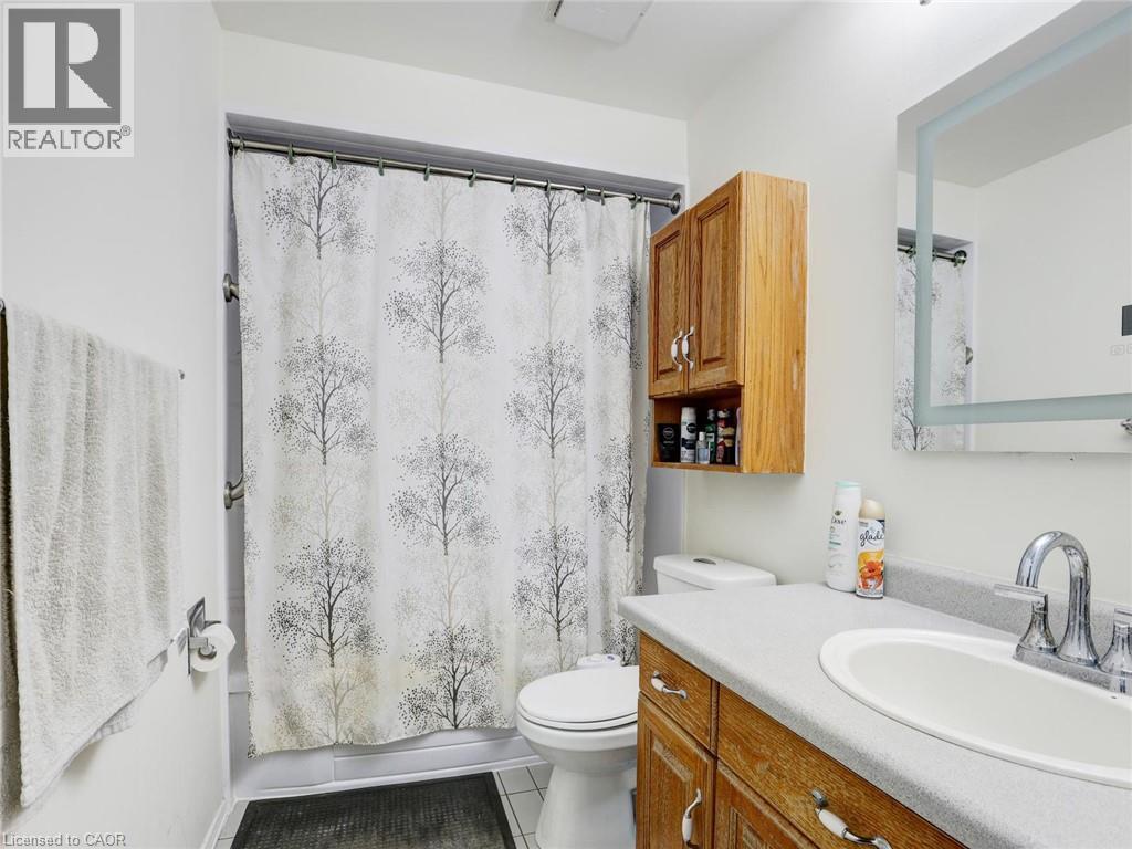 Spa-inspired bathroom featuring a wood-finish vanity with dual-sink configuration, white countertop, and chrome faucetry - 128 Macatee Place, Cambridge, ON - Indoor Photo Showing Bathroom