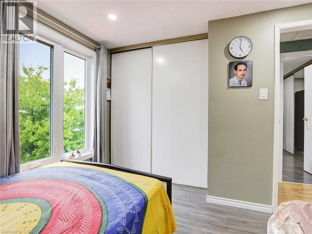 Bright bedroom retreat featuring expansive glass doors framed in natural wood trim, abundant natural light, and hardwood flooring - 128 Macatee Place, Cambridge, ON - Indoor Photo Showing Bedroom