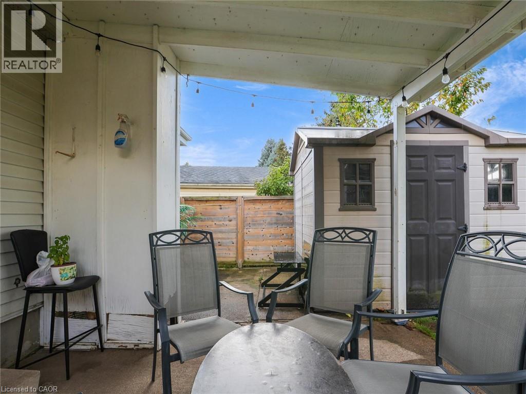 Covered patio with concrete flooring and overhead beam construction, featuring multiple lounge chairs and a small side table - 128 Macatee Place, Cambridge, ON - Outdoor With Exterior