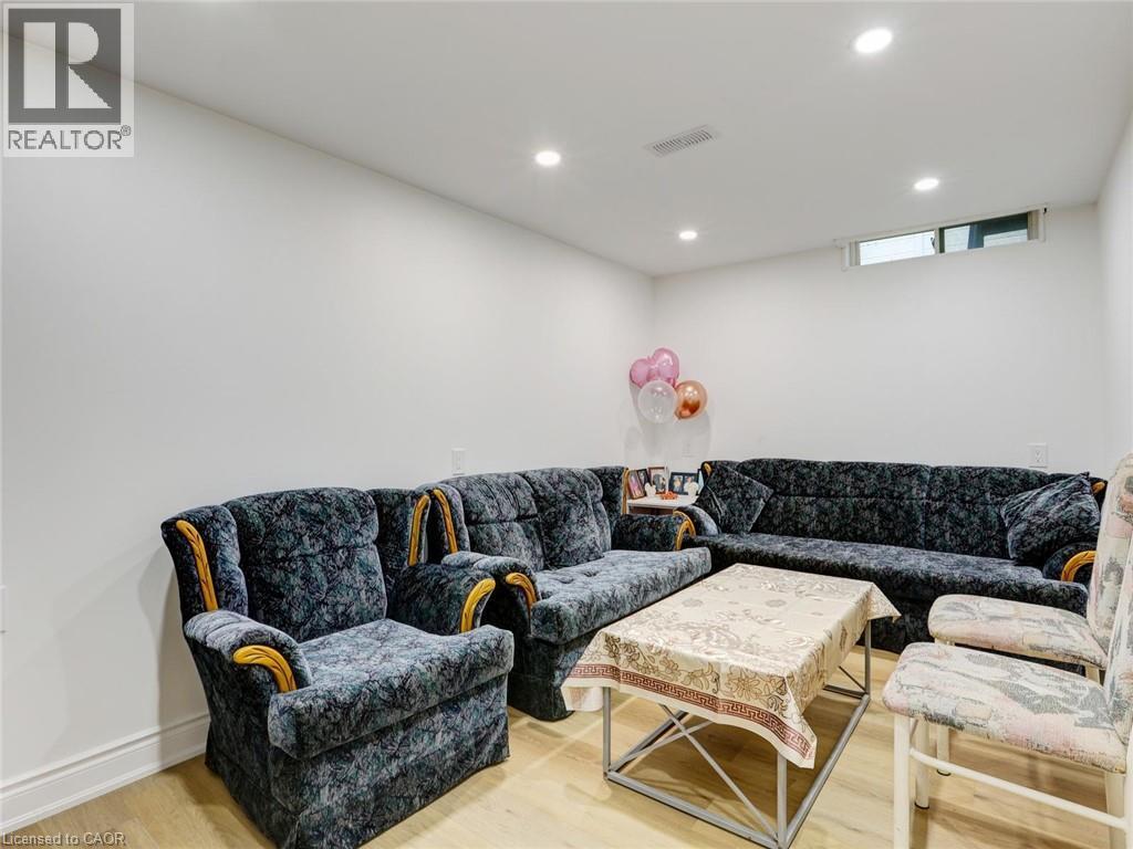 Finished Basement Recreation Room with Recessed Ceiling Lighting, Plush Upholstered Sectional Sofa with Nailhead Trim, Wood-Finish Flooring, and Ample Square Footage for Entertainment and Leisure Acti - 128 Macatee Place, Cambridge, ON - Indoor