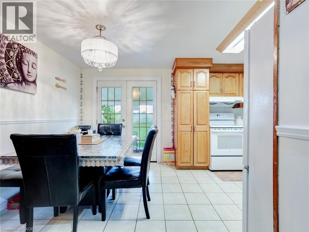 Kitchen with wood-finish cabinetry, white appliances, and tiled flooring - 128 Macatee Place, Cambridge, ON - Indoor Photo Showing Dining Room
