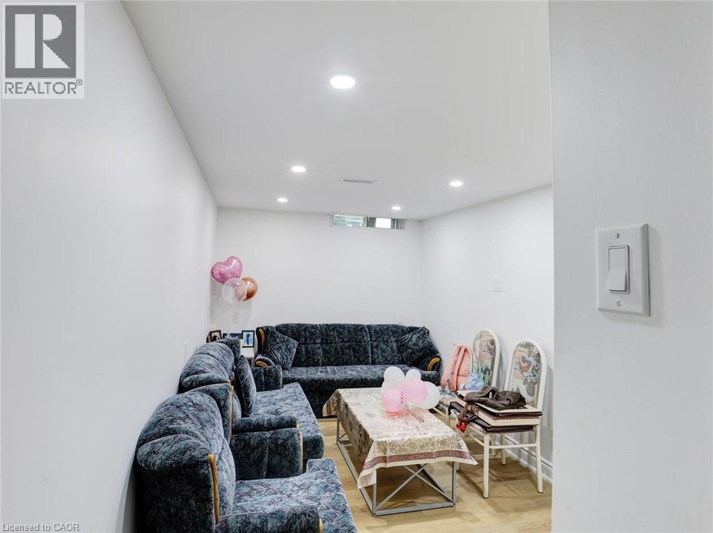 Finished basement recreation room featuring recessed ceiling lighting, wood-finish flooring, and ample space for entertainment and leisure activities - 128 Macatee Place, Cambridge, ON - Indoor