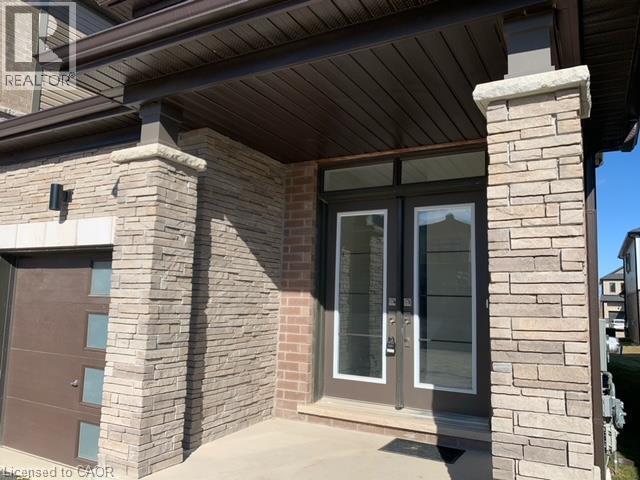 Stone veneer facade, covered entry, double entry doors, transom window, and integrated garage door - 16 Monteith Drive, Brantford, ON - Outdoor With Exterior