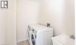 Utility room featuring a laundry basin with chrome faucet and tile flooring - 