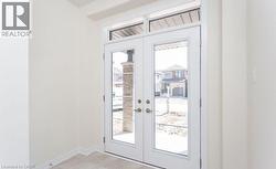 Double entry doors with transom window, light-toned walls, and neutral-toned floor tile - 