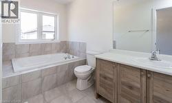 Built-in soaking tub, large window, wood-finish vanity, integrated sink, and tiled flooring - 