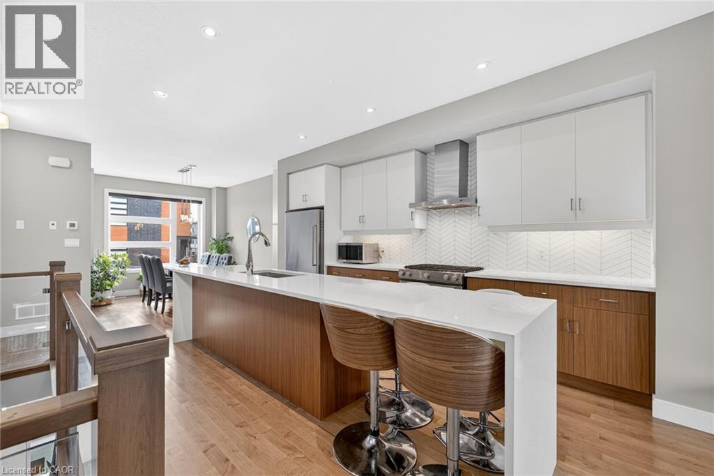 Open-concept kitchen with a waterfall island, stainless steel appliances, wood-finish flooring, and two-tone cabinetry - 60 Arkell Road Unit# 57, Guelph, ON - Indoor Photo Showing Kitchen With Upgraded Kitchen