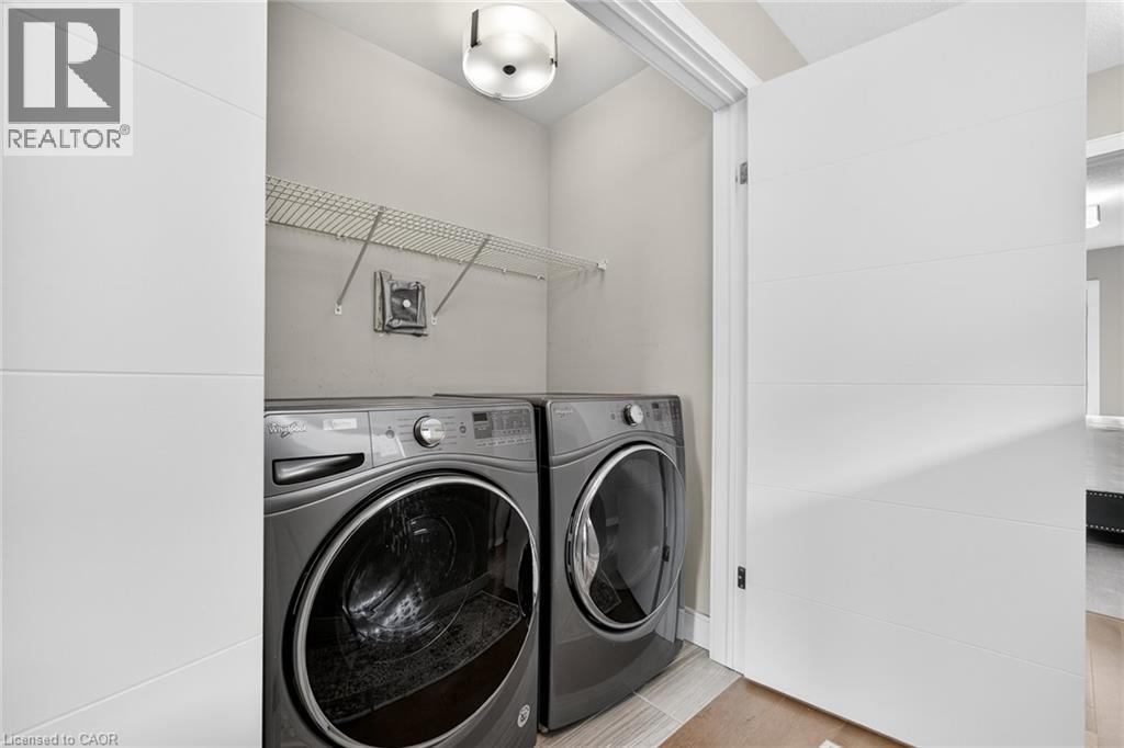 Dedicated laundry space with wire shelving, modern flush mount lighting, and wood-finish flooring - 60 Arkell Road Unit# 57, Guelph, ON - Indoor Photo Showing Laundry Room