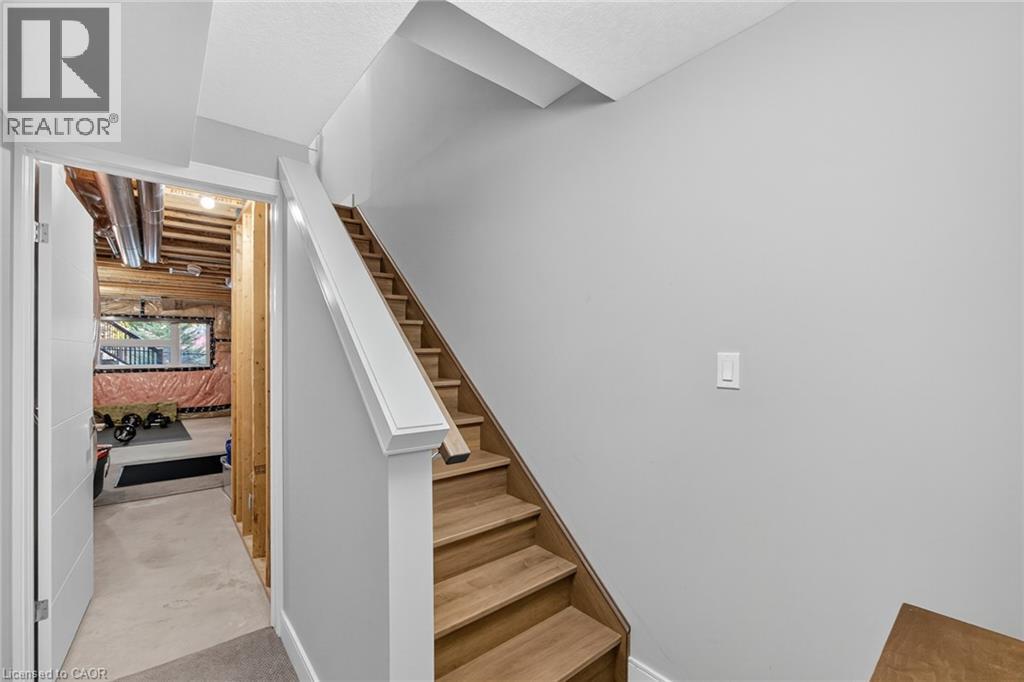 Wood-finish staircase with white risers and handrail, neutral wall paint, and overhead lighting - 60 Arkell Road Unit# 57, Guelph, ON - Indoor Photo Showing Other Room