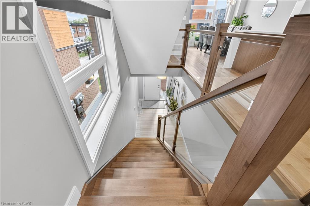 Wood-finish flooring throughout, modern wood and glass railing, and large windows providing ample illumination - 60 Arkell Road Unit# 57, Guelph, ON - Indoor Photo Showing Other Room