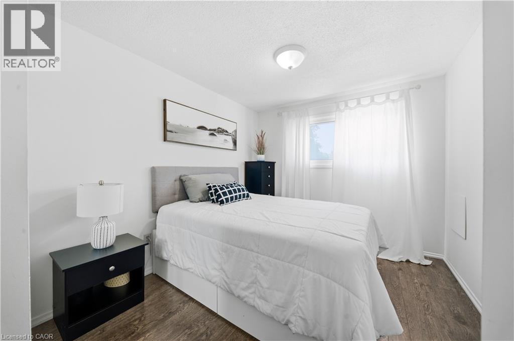 Wood-finish flooring, recessed window with sheer drapery, and a contemporary flush-mount ceiling light - 230 Sunset Boulevard, Cambridge, ON - Indoor Photo Showing Bedroom