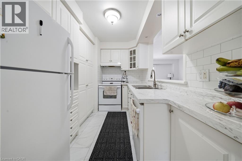 Kitchen featuring white cabinetry, white subway tile backsplash, light-colored countertops, and stainless steel sink - 230 Sunset Boulevard, Cambridge, ON - Indoor Photo Showing Kitchen With Double Sink