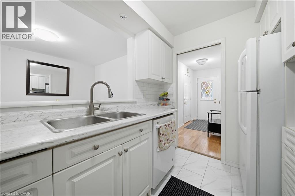 Kitchen featuring white cabinetry, a double basin stainless steel sink, a pull-down faucet, and white countertops - 230 Sunset Boulevard, Cambridge, ON - Indoor Photo Showing Kitchen With Double Sink