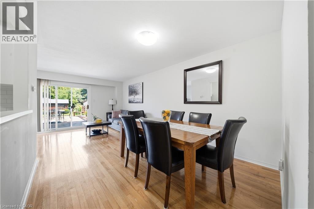 Hardwood flooring throughout, sliding glass door, white walls, flush mount ceiling light, and a built-in half-wall with tile accent - 230 Sunset Boulevard, Cambridge, ON - Indoor Photo Showing Dining Room
