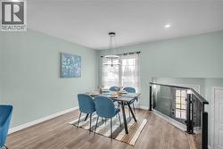 Dining space featuring wood-finish flooring, light green walls, and a modern chandelier - 
