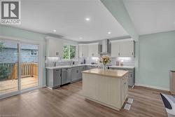Contemporary kitchen featuring wood-finish flooring, a central island, and two-tone cabinetry with under-cabinet lighting - 