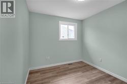 Interior room featuring wood-finish flooring, light-colored walls, and a window with white trim - 