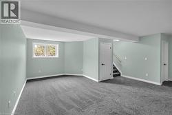 Spacious room featuring light green walls, gray patterned carpeting, and white trim - 
