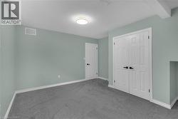 Room featuring plush gray carpeting, light green wall paint, and white baseboards - 