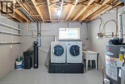 Dedicated laundry area featuring a utility sink, front-loading washer and dryer, and exposed ceiling joists - 