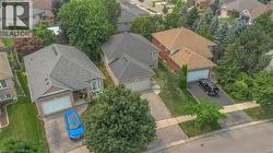 Residential street featuring a brick-front home with an attached garage, a paved driveway, and mature landscaping - 